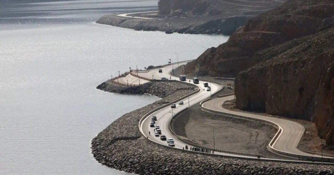 Vista de la costa rocosa y el mar en Khasab, Omán, con barcos en el horizonte durante el atardecer.