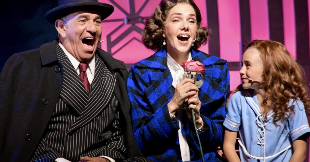 Elenco de la obra musical Annie en escena, con la actriz que interpreta a la protagonista y el perro Sandy.